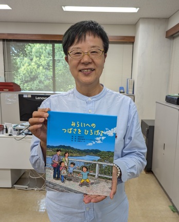 絵本「みらいへの　つばさを　ひろげて」を持つ萩原なつ子の写真