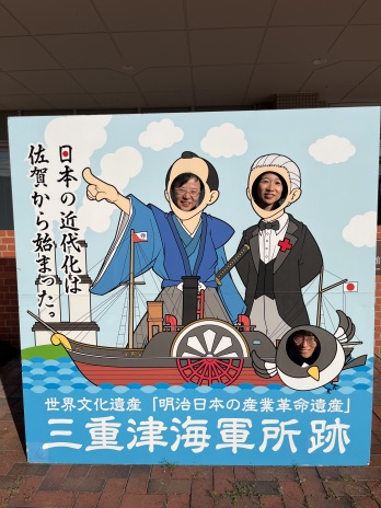 三重津海軍所跡の看板で記念撮影をする萩原なつ子の写真