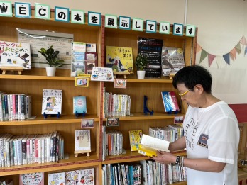 展示コーナーで本を読む萩原なつ子の写真