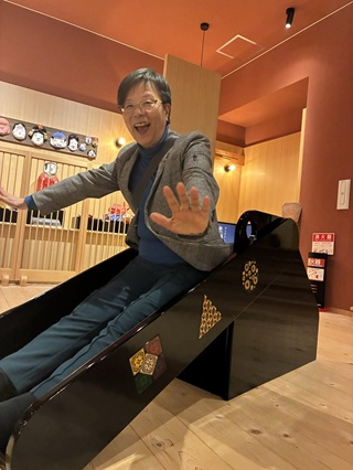 漆塗りのすべり台を滑る萩原なつ子