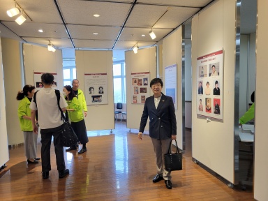 パネル展の前に立つ萩原なつ子の写真