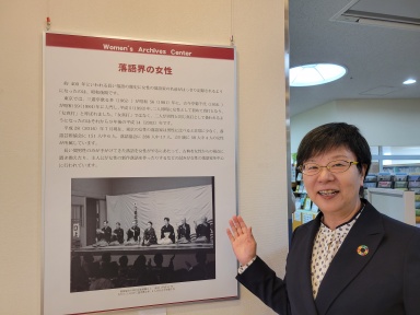 「落語会の女性」という展示パネルを指す萩原なつ子の写真