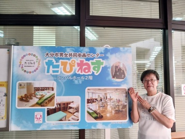 たぴねすの看板を指す萩原なつ子の写真