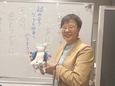 川柳が書かれたホワイトボードの前に立つ萩原なつ子の写真