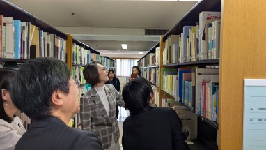 三原大臣が本棚を見ている写真